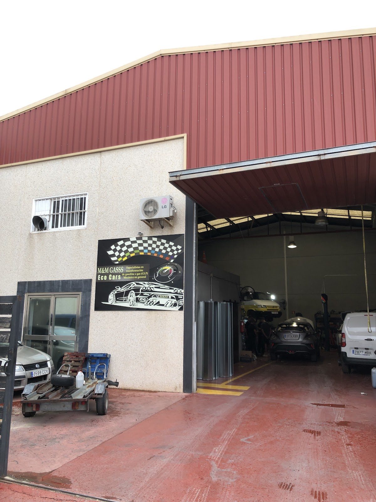 Nave del taller m&m gasss con techo rojo y la entrada de los talleres